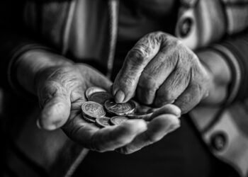 Close-up of elderly hands holding and counting coins, captured in black and white for a timeless feel.