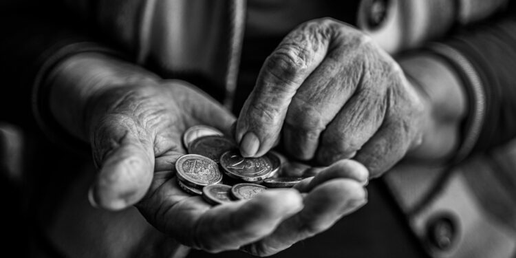 Close-up of elderly hands holding and counting coins, captured in black and white for a timeless feel.