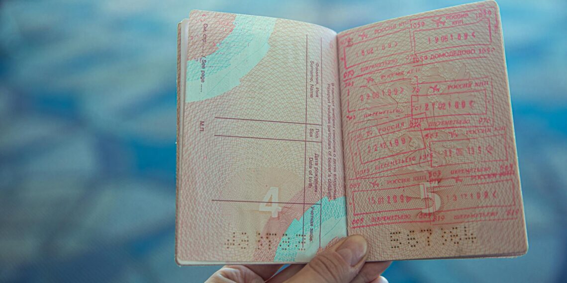 Close-up view of an open passport displaying various travel stamps in an airport setting.