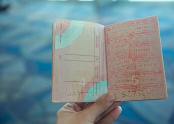 Close-up view of an open passport displaying various travel stamps in an airport setting.