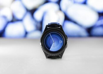 A sleek digital smartwatch with a blue interface against an abstract blurred background. Stylish and modern.