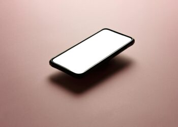 A smartphone with a blank white screen on a pink background, perfect for mockups.
