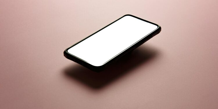A smartphone with a blank white screen on a pink background, perfect for mockups.
